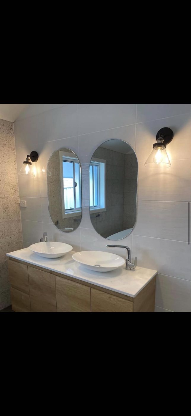 Backlit mirrors and wall lights over a double vanity