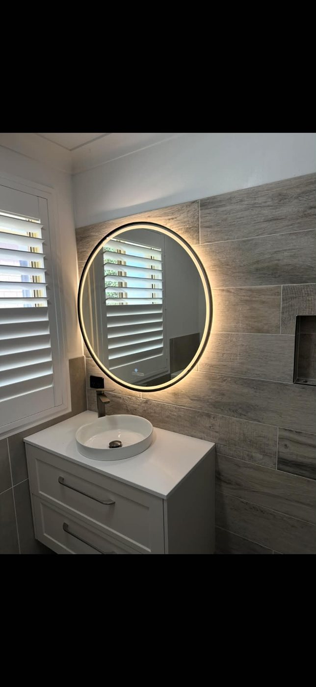 Backlit round mirror in a renovated bathroom